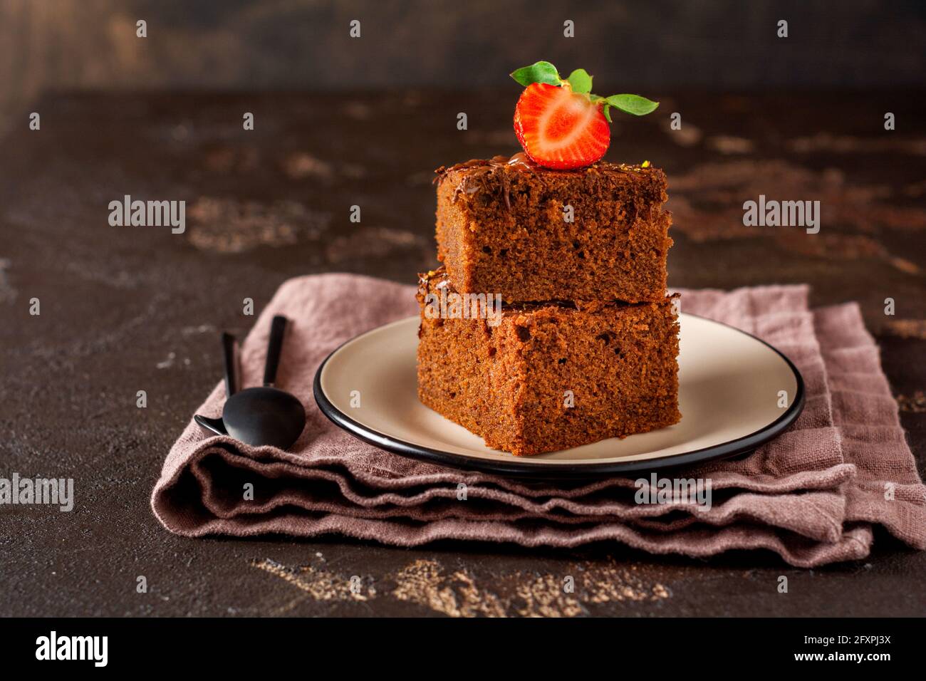 Pila di pezzi o barretta di brownie torta al cioccolato con fragole e pistacchio noci su sfondo nero, immagine fuoco selettivo Foto Stock