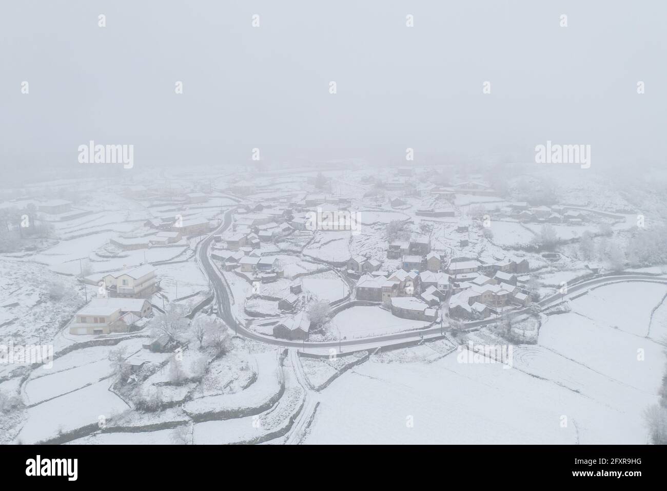 Drone vista aerea di una strada e remoto villaggio coperto di neve a Vila Real, Norte, Portogallo, Europa Foto Stock