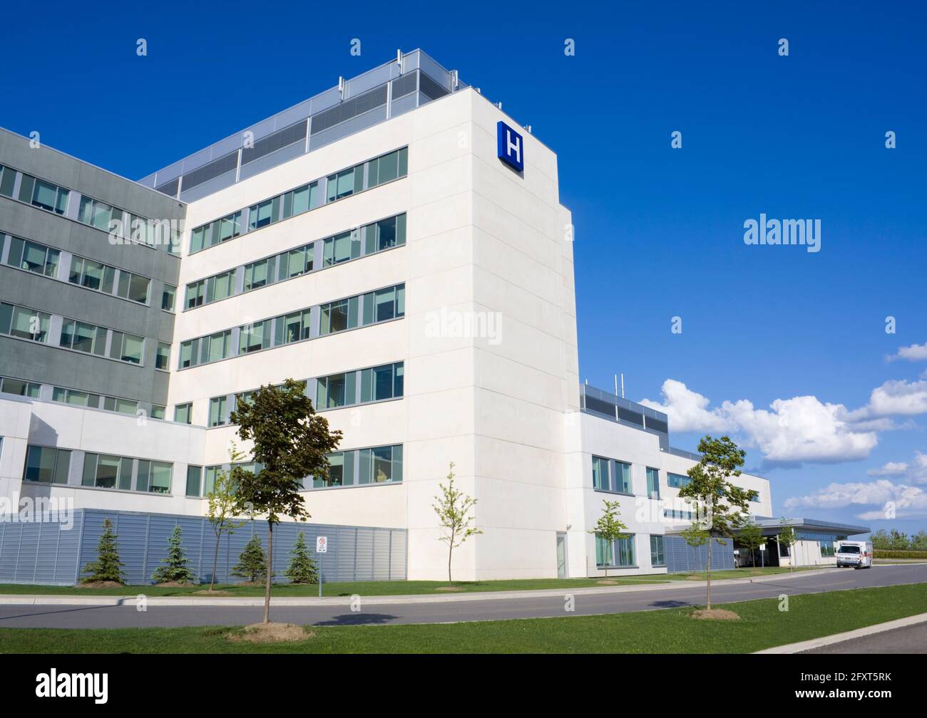 Ospedale moderno con ambulanza parcheggiata sulla strada Foto Stock