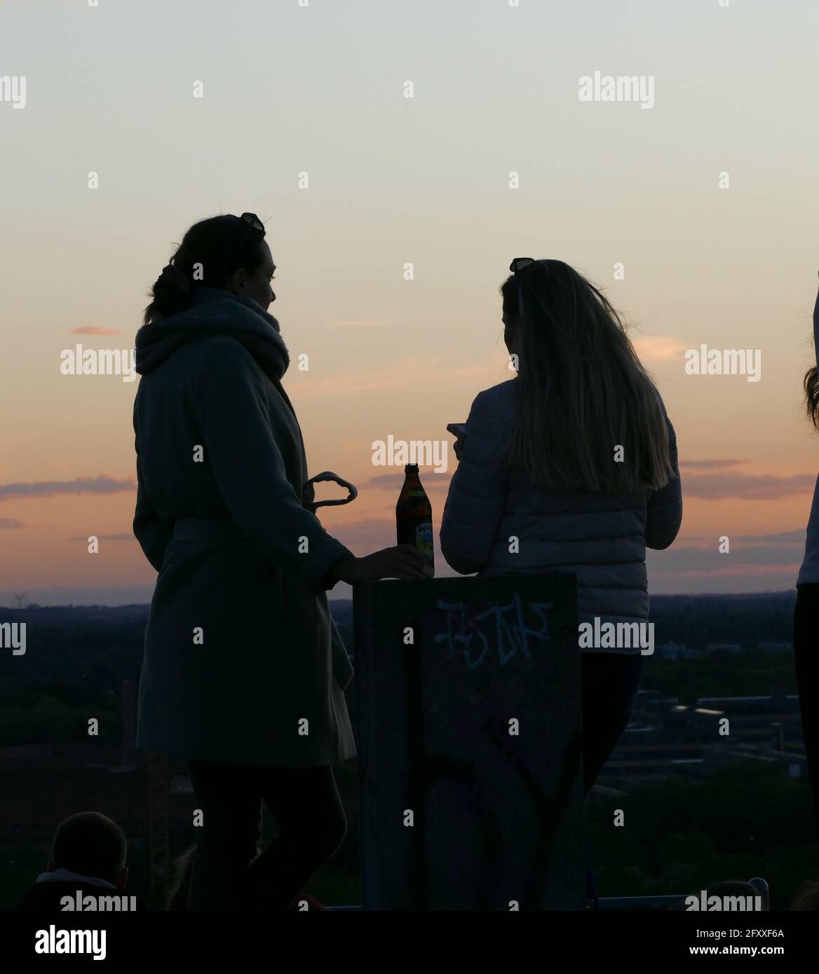 Sillhouettes di 2 amici che trascorrono il loro tempo dopo il lavoro sorseggiando un drink su una montagna urbana . Foto Stock