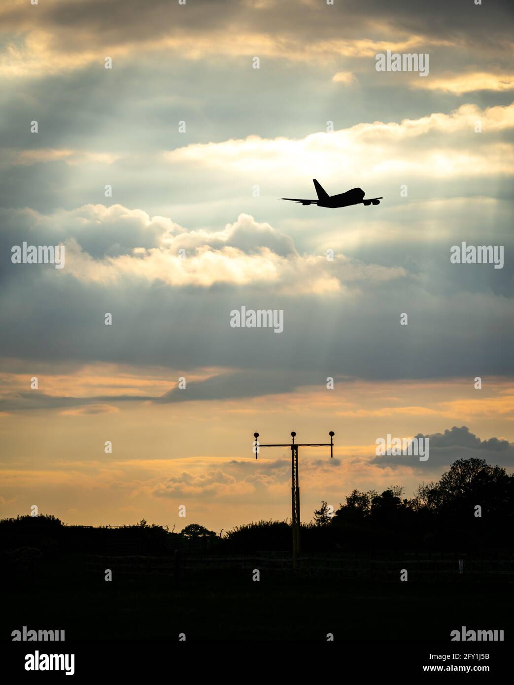 Jumbo Jet quattro grandi motori che volano fuori portando i turisti all'estero dall'aeroporto in vacanza nel cielo estivo del tramonto dorato. Nuvole e silhouette color oro cremoso Foto Stock