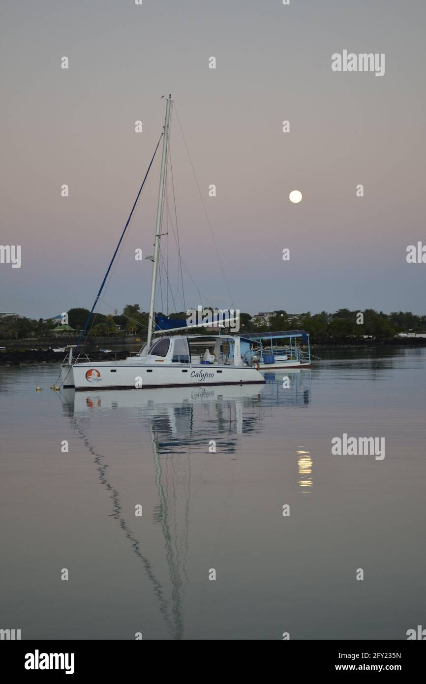 Foto di mattina presto di un catamarano e di una luna lungo la costa di Grand Baie, isola di Mauritius, Oceano Indiano Foto Stock