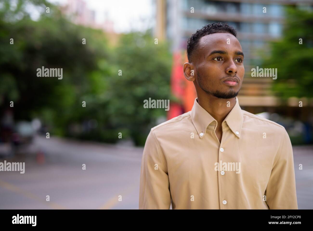 Ritratto di bello nero giovane uomo d'affari africano pensare all'aperto in città Foto Stock
