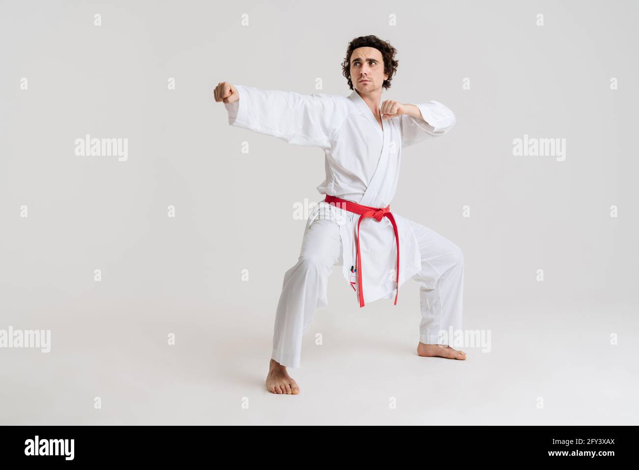 Uomo Karate che si esercita isolato su sfondo bianco Foto Stock