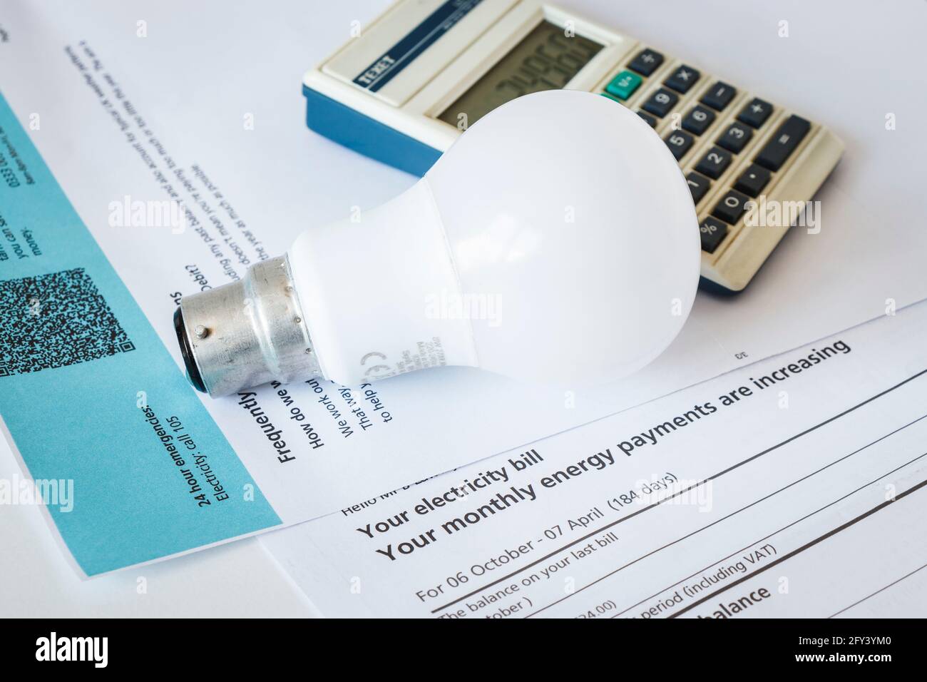 Immagine concettuale di una lampadina e di una calcolatrice elettrica con attacco a baionetta su una bolletta elettrica che notifica un aumento delle spese Foto Stock