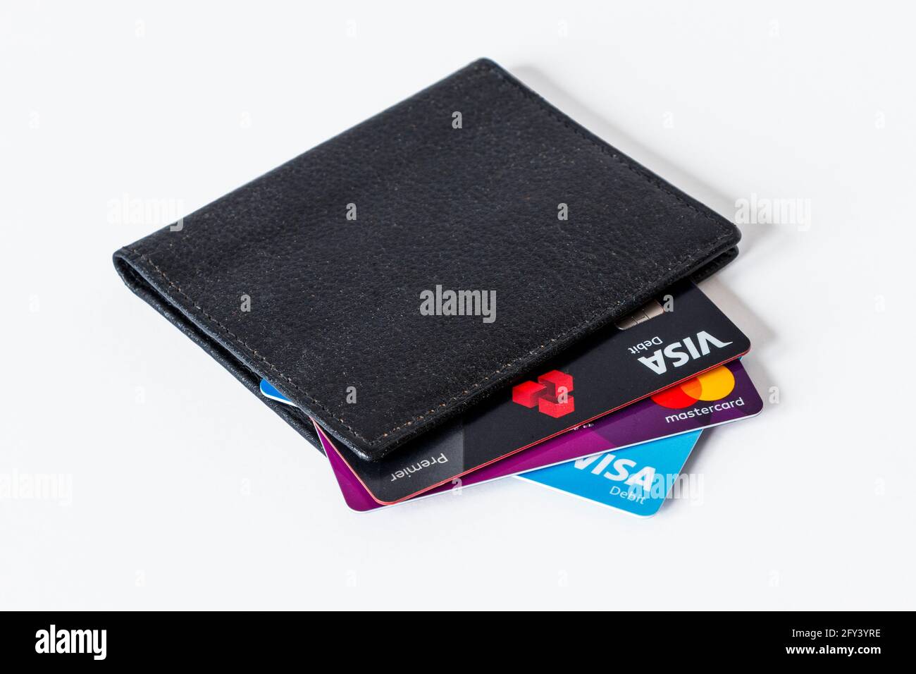 Un porta carte di credito in pelle nera con carte di credito e di debito visualizzate, su sfondo bianco Foto Stock