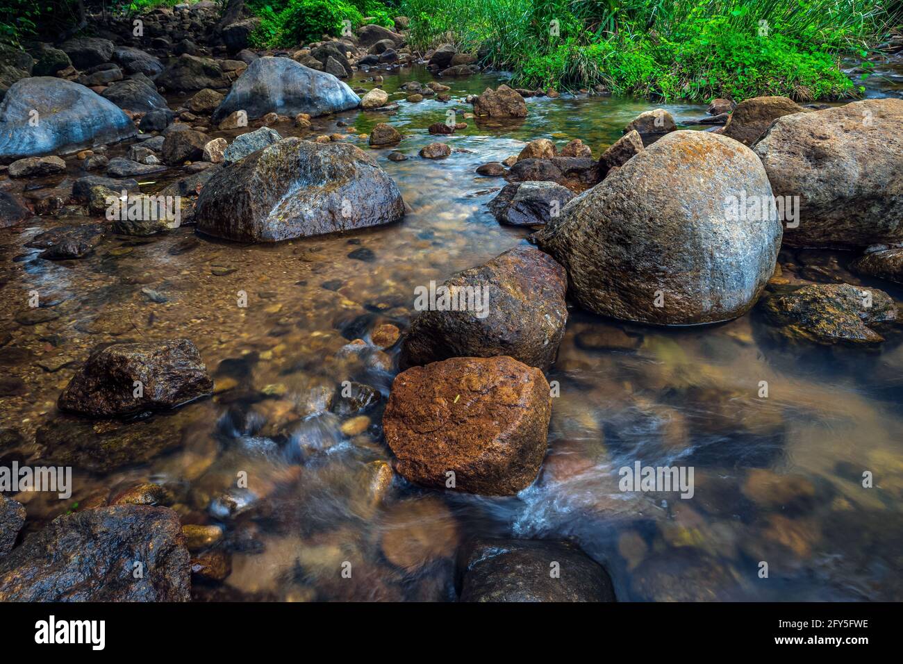 Acqua che scorre attraverso pietre e giù piccoli gradini di roccia scena naturale. Foto Stock