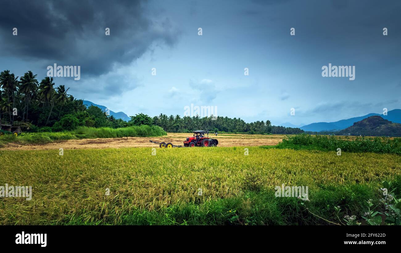 Trattore moderno con ex impianto di raccolta riso con sfondo naturale di montagna. NAGERCOIL, distretto di Kanyakumari. India del Sud. Foto Stock