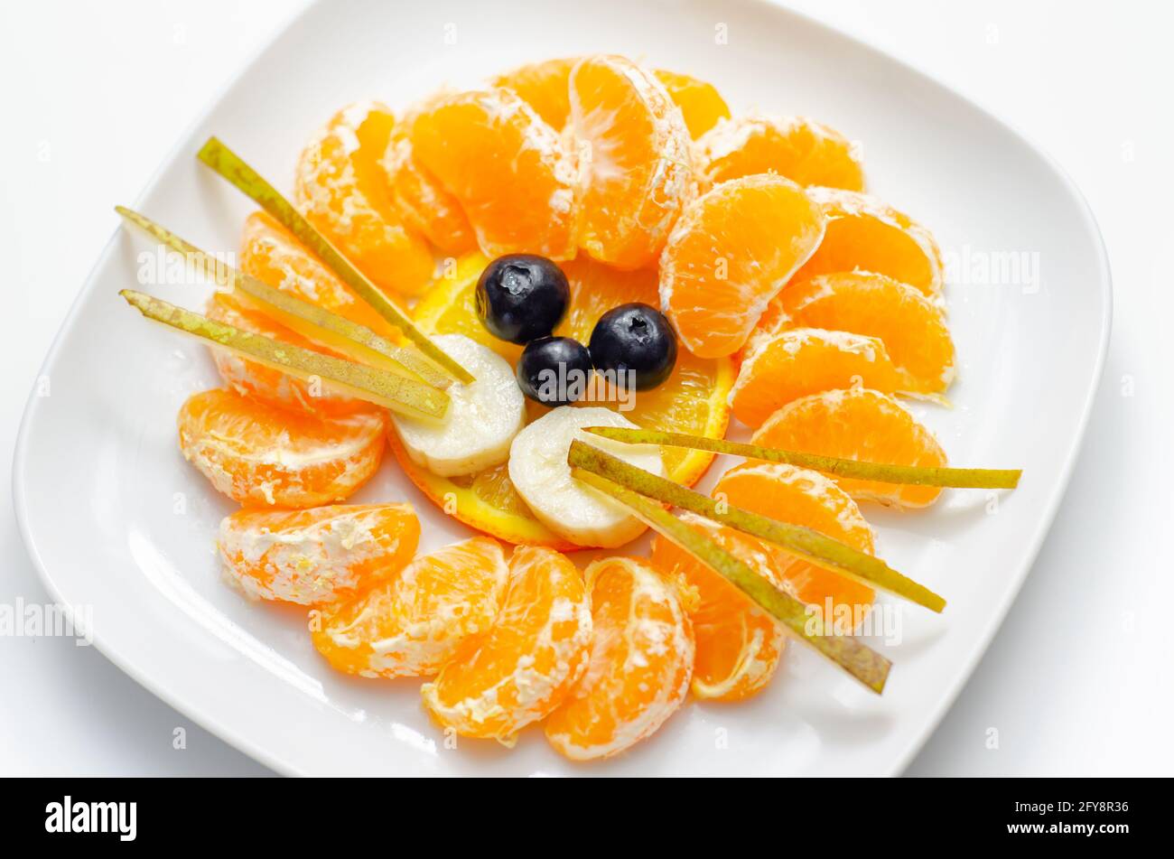 Frutta fresca, arancio, mandarino, banana, uva e pera serviti in modo creativo, spuntino a base di leoni, cibo divertente Foto Stock