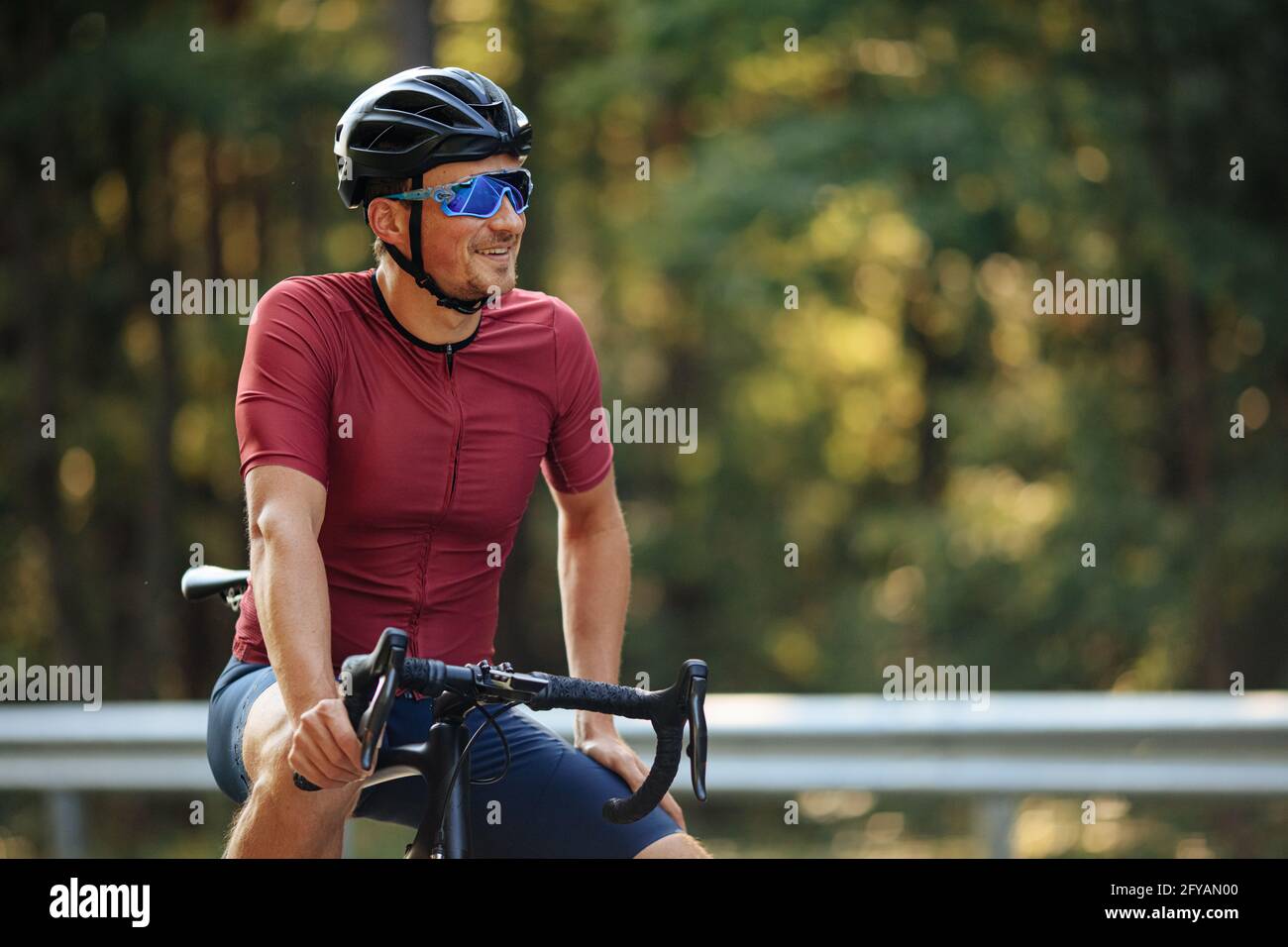 Uomo sorridente con bici nera rilassante all'aperto Foto Stock