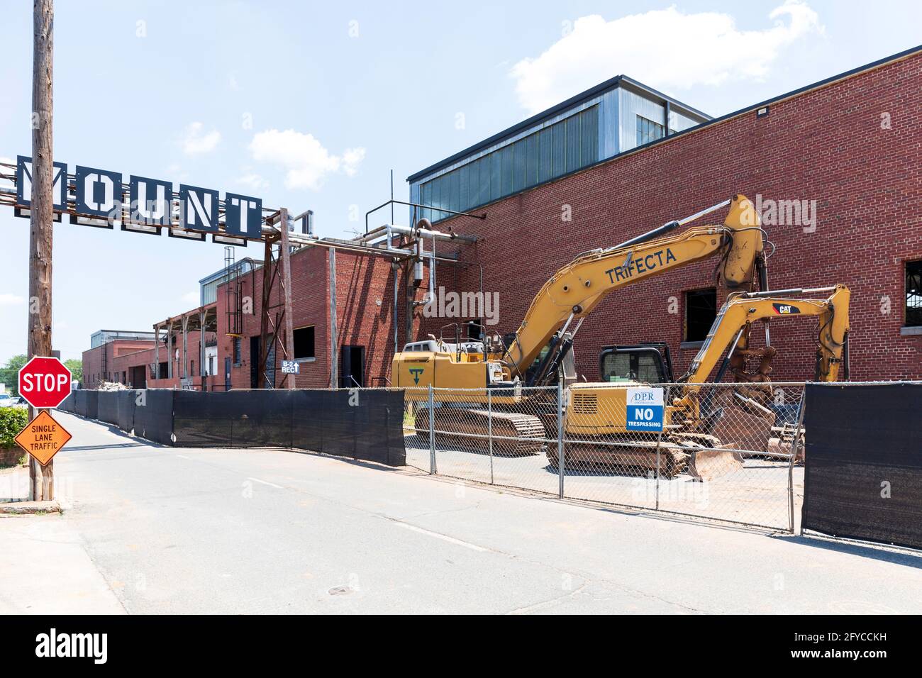 CHARLOTTE, NC, USA-23 MAGGIO 2021: Camp North End. Cartello per il quartiere 'Monte', due trattori con retroescavatori, edificio in mattoni. Foto Stock