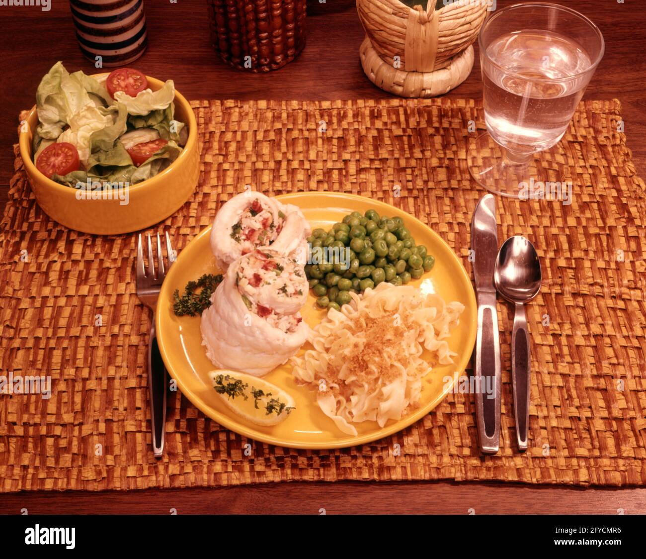 1970 CENA AMERICANA NORMALE VENERDÌ TAVOLO PIATTO CIBO PESCE PISELLI INSALATA NOODLE PASTA LIMONE ACQUA FILETTO UNICO POSTO - KF10230 WOD001 HARS POLLAME AGRUMI VECCHIO STILE Foto Stock