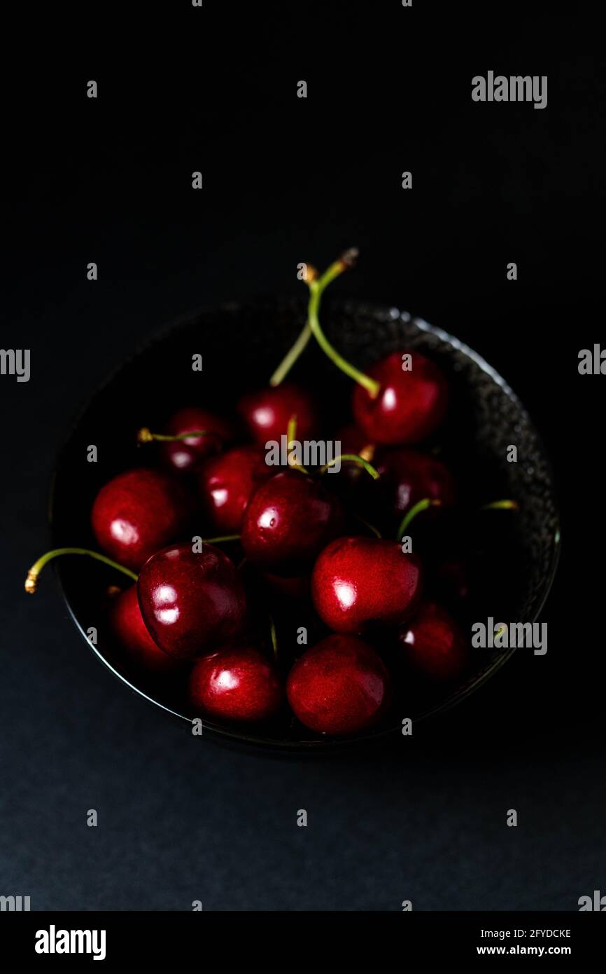 fresche ciliegie rosse succose in un piccolo recipiente nero Foto Stock