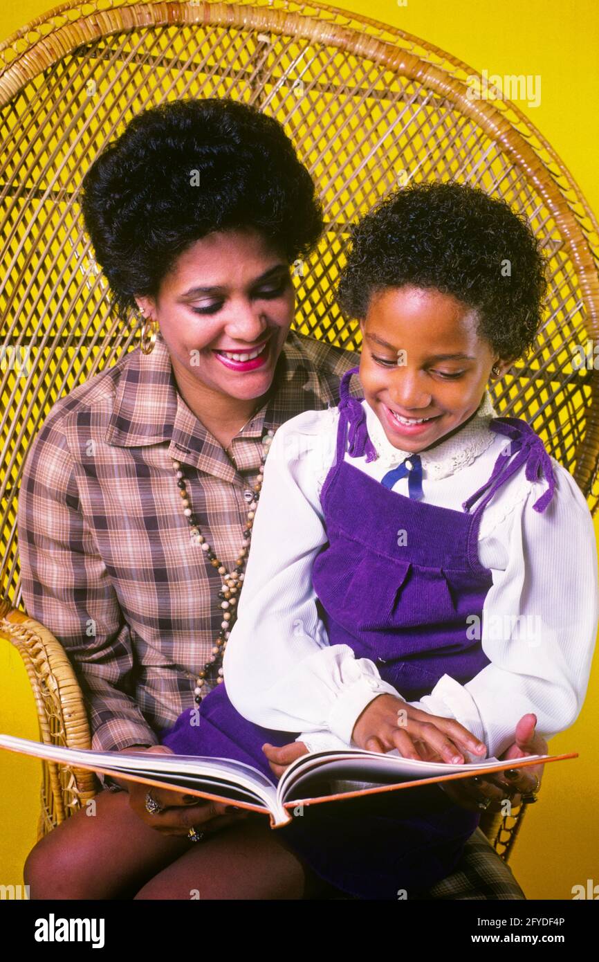 ANNI OTTANTA SORRIDENTE AFROAMERICANA MADRE E FIGLIA AFRO ACCONCIATURA SEDUTA DENTRO SEDIA DI PAGLIA DI RATTAN CON SCHIENALE ALTO CHE LEGGE UN LIBRO - KJ11213 TRA001 MADRI HARS VECCHIO TEMPO FUTURO NOSTALGIA VECCHIA MODA 1 COMUNICAZIONE DI STILE GIOVANILE INFORMAZIONI DI LAVORO DI SQUADRA SODDISFAZIONE DI STILE DI VITA CELEBRAZIONE FEMMINILE SALUTE VITA DOMESTICA METÀ-LUNGHEZZA DONNE FIGLIE PERSONE AFRO OBIETTIVI DI CURA SUCCESSO RATTAN FELICITÀ BENESSERE AFROAMERICANI AFROAMERICANI E SCELTA EMOZIONE ACCONCIATURA PROGRESSO RICREAZIONE ETNIA NERO ORGOGLIO OPPORTUNITÀ AUTORITÀ IMMAGINAZIONE CONCETTUALE SOSTEGNO ELEGANTE IDEE DI CRESCITA SUPPORTATE GIOVANI Foto Stock