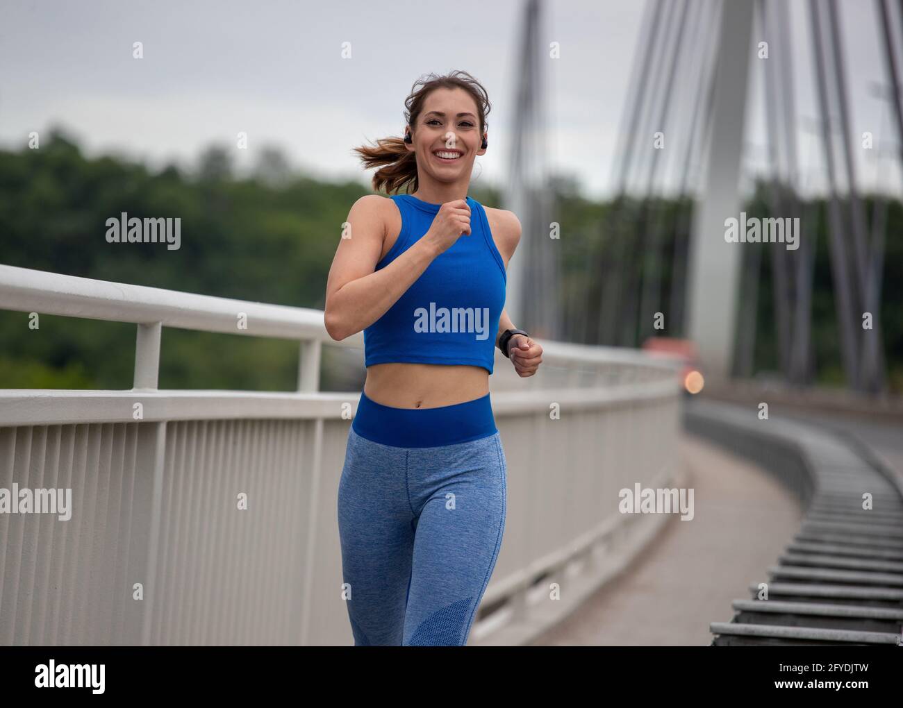 Fit giovane donna in abbigliamento sportivo jogging sul ponte durante il giorno. Concetto di stile di vita sano e attivo Foto Stock