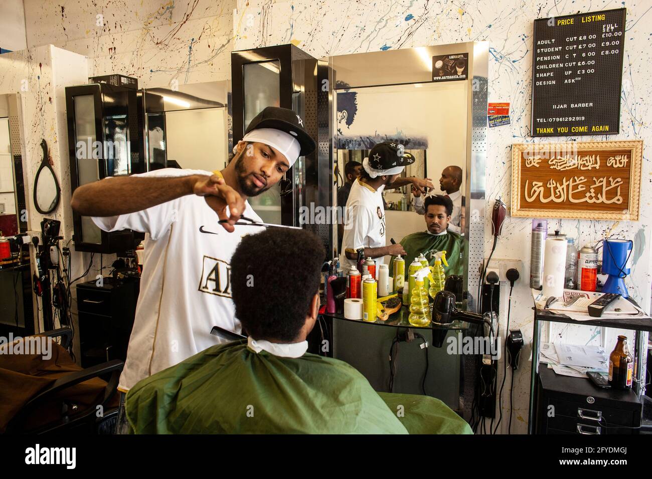Un parrucchiere dà una forbici taglio di capelli al cliente al barbiere a Londra, Regno Unito Foto Stock