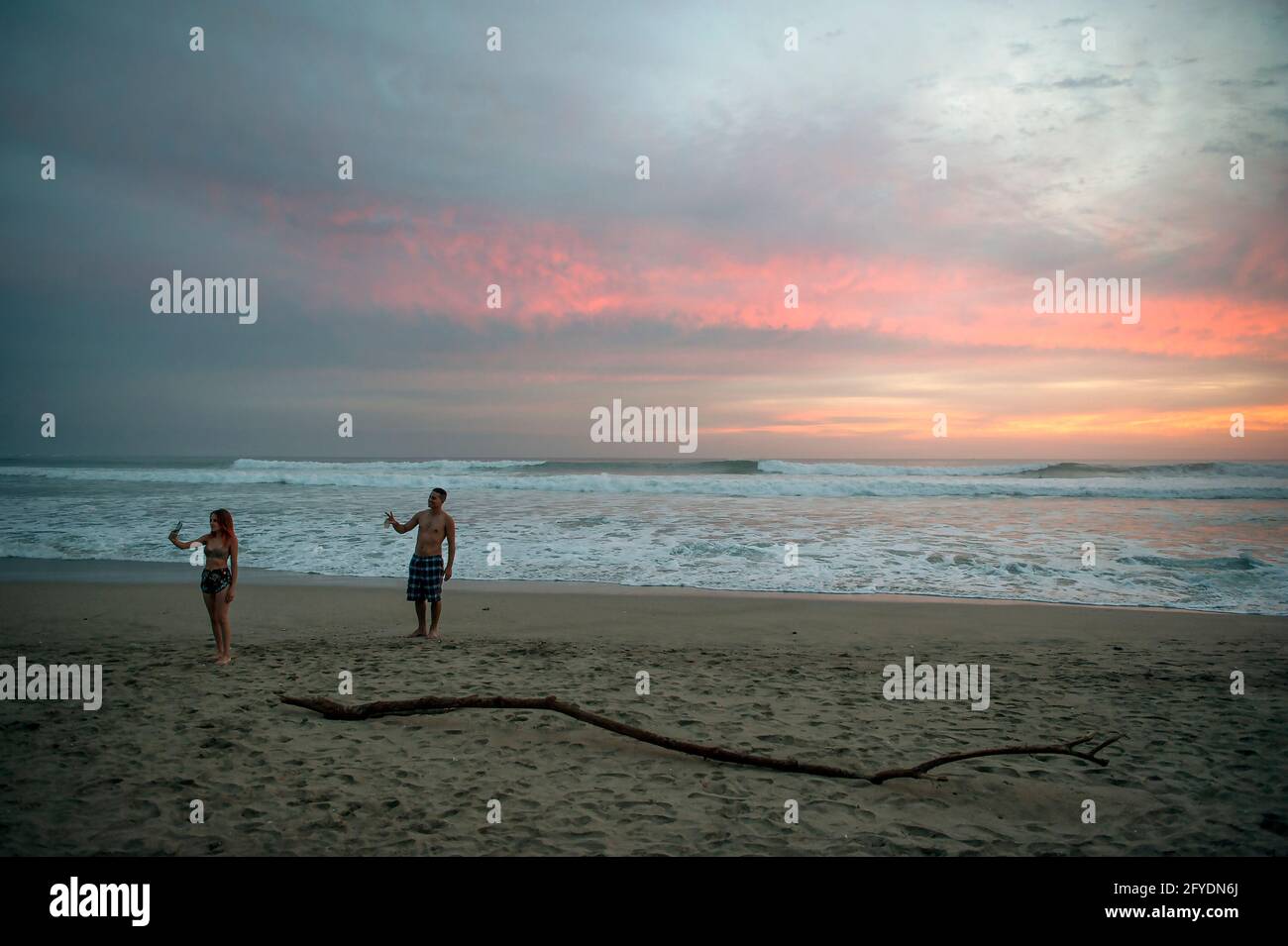 Coppia che prende un selfie sulla spiaggia al tramonto a Tamarindo, Costa Rica Foto Stock