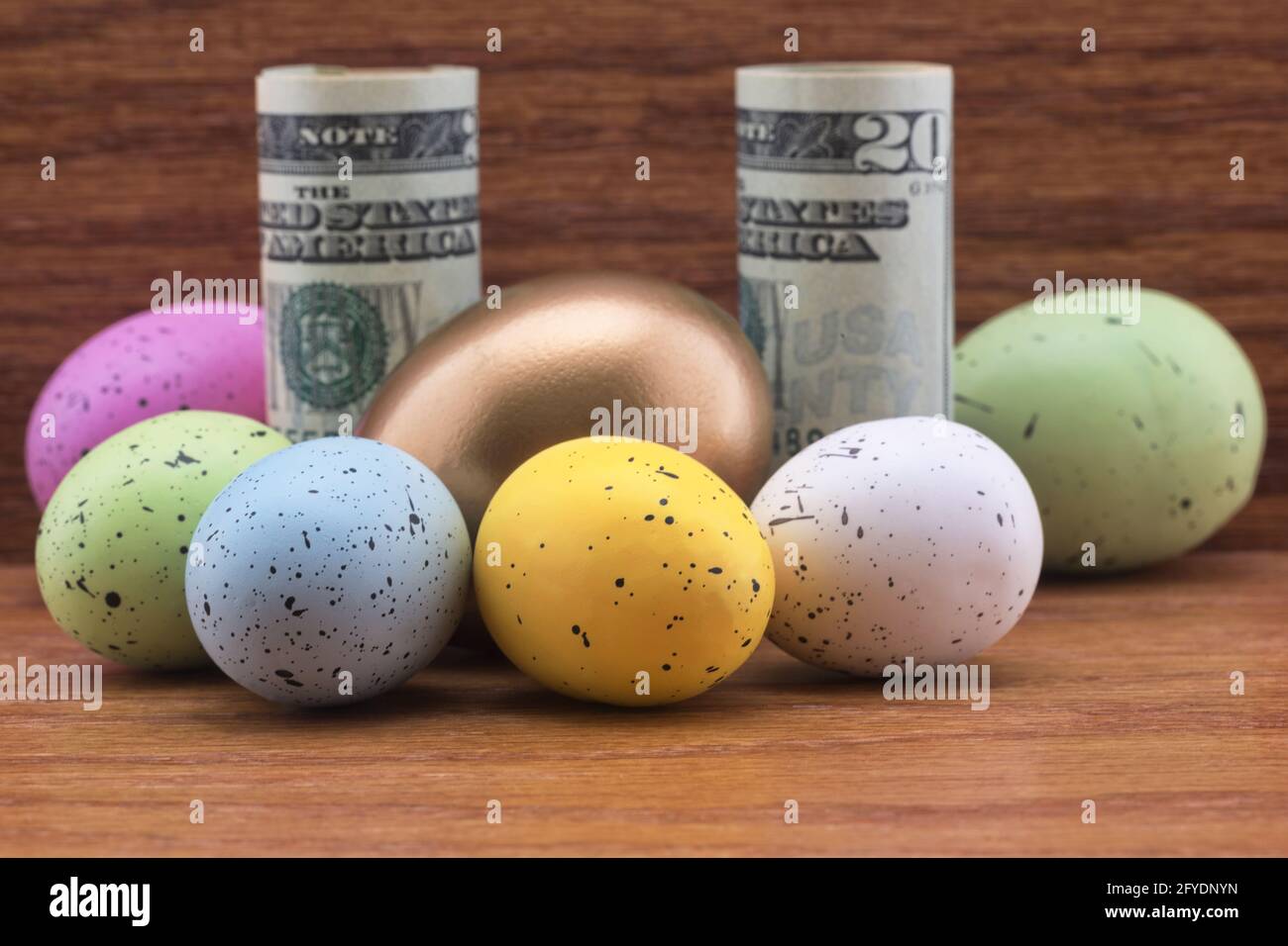 La valuta americana circondata da uova di nido d'oro e sei uova colorate riflette la diversificazione di successo nei simboli concettuali di investimento aziendale. Foto Stock