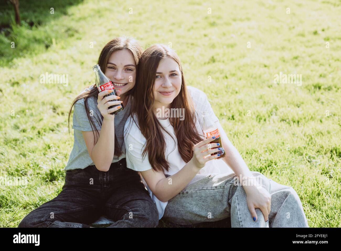 Buche, Ucraina, 26 maggio 2021. Belle giovani donne adolescenti in una calda giornata estiva con bottiglie di vetro di Coca-Cola nelle loro mani, sorridendo felice. Morbido Foto Stock