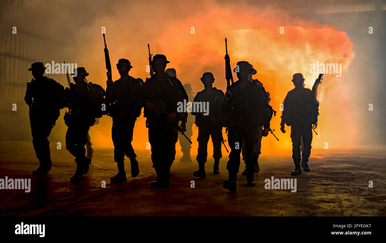 Silhouette di soldati durante la missione militare al crepuscolo Silhouette di soldati dell'esercito nella nebbia contro un tramonto, marines squadra in azione Foto Stock