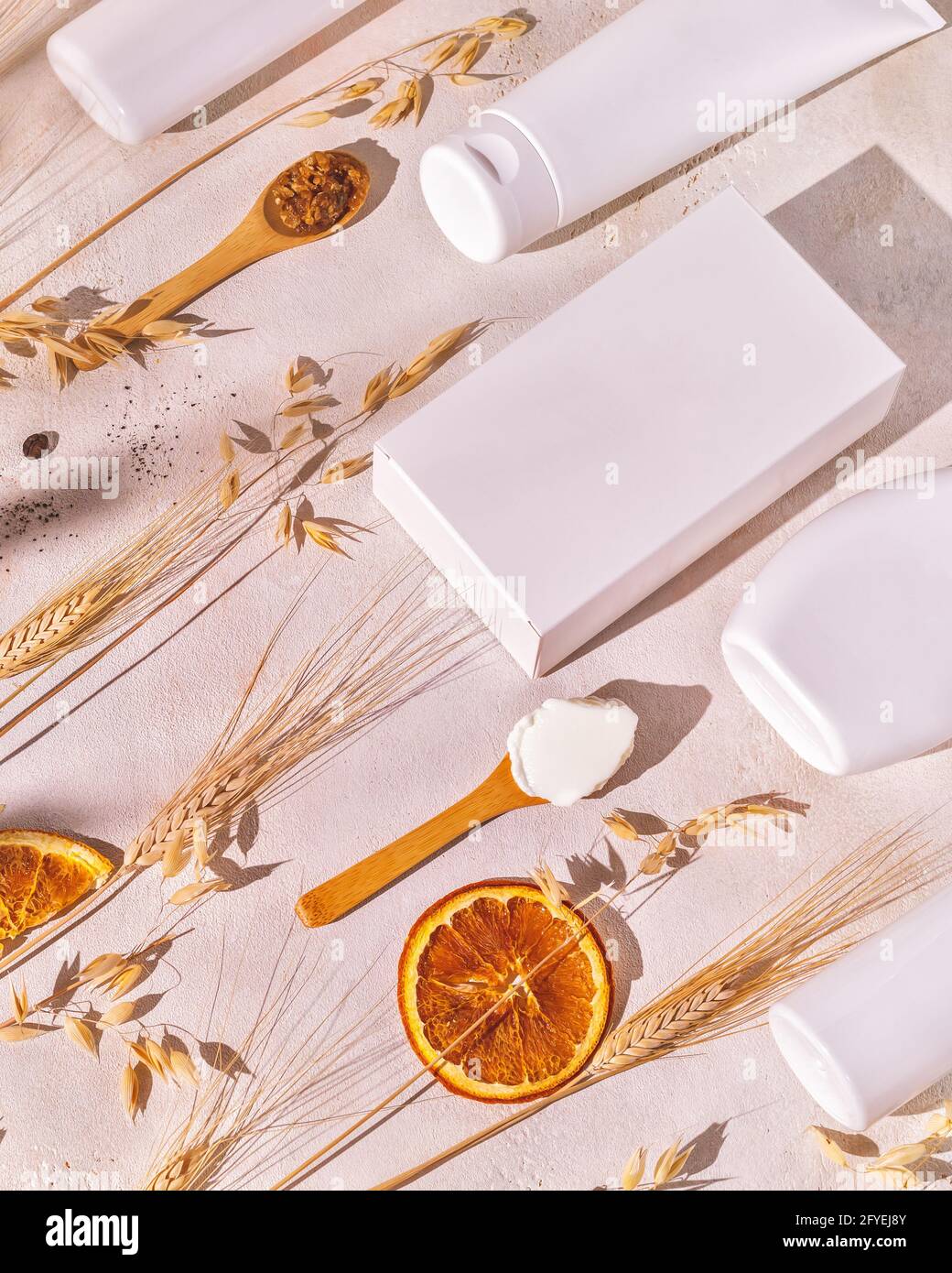 Composizione verticale spa con bottiglie cosmetiche, scatole, cucchiai di legno con ingredienti naturali, orecchie di segale e grano. Prodotti di bellezza mock up Foto Stock