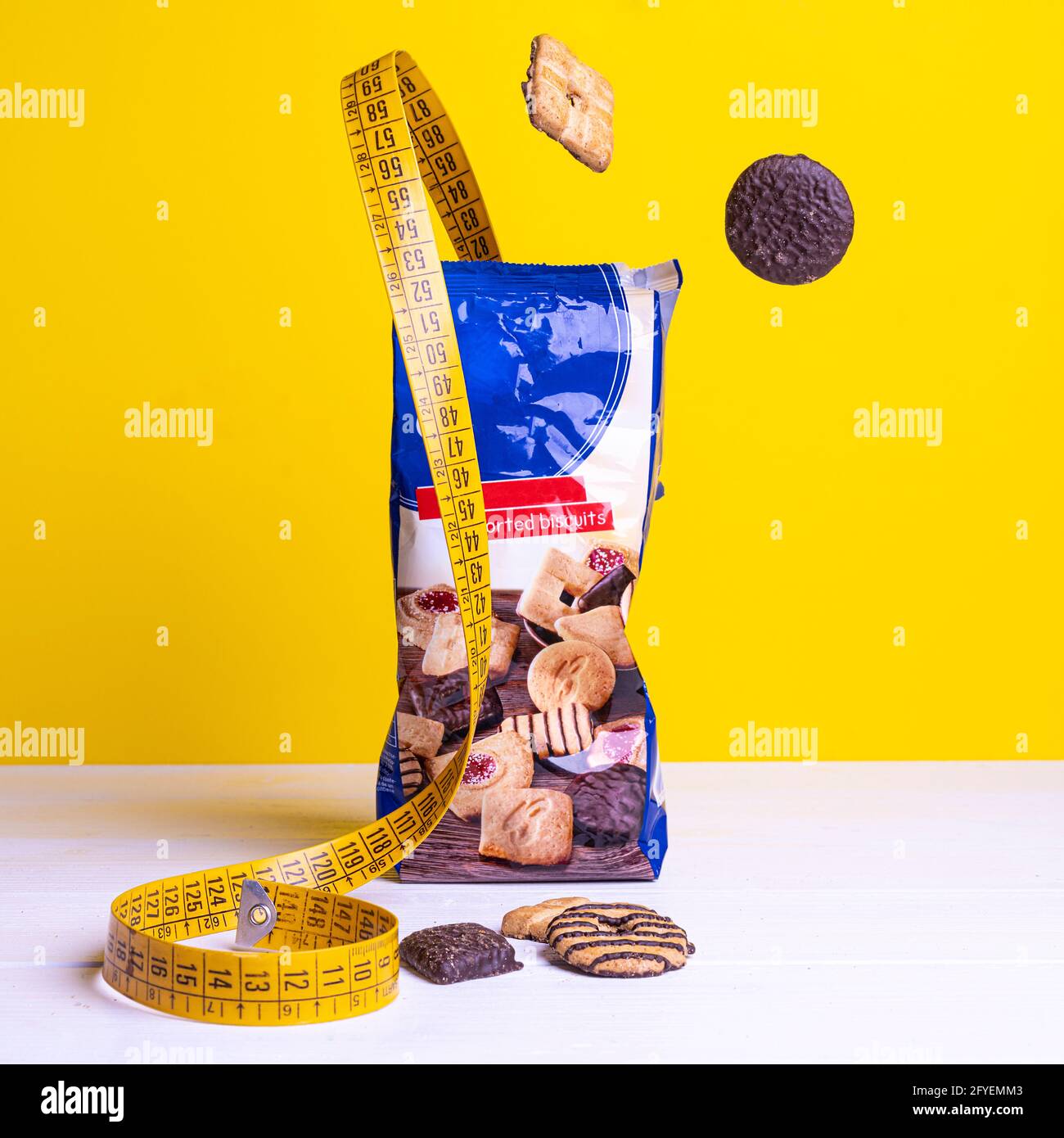 un metro a nastro tra alcuni biscotti su una superficie colorata. Foto Stock un metro a nastro tra alcuni biscotti su una superficie colorata. Foto Stock