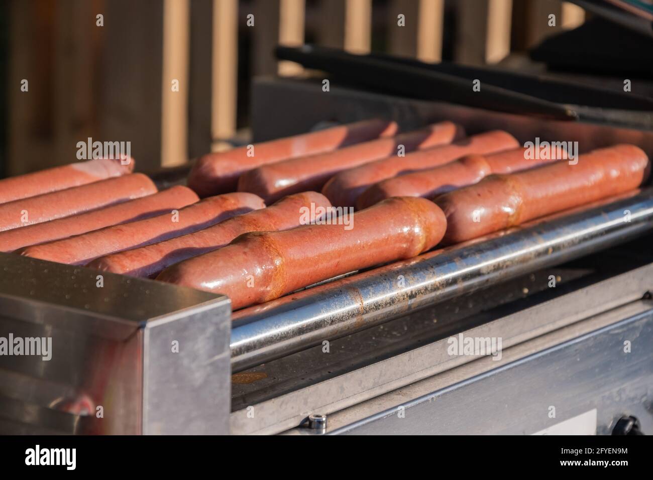 Le salsicce di cani caldi vengono fritte su una macchina da cucina rotante in una caffetteria all'aperto Foto Stock