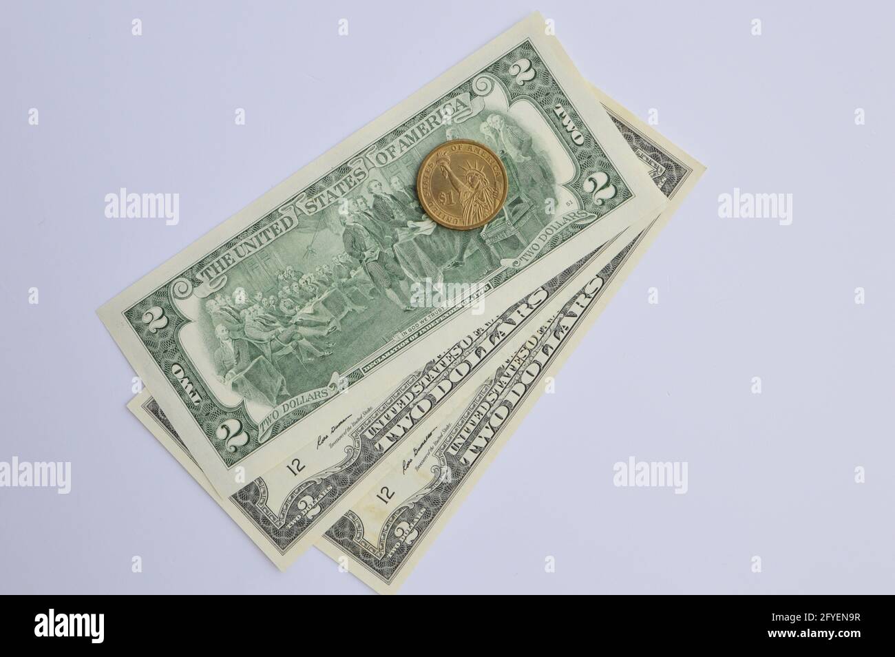 Una moneta in dollari USA e due banconote in dollari su sfondo bianco Foto Stock