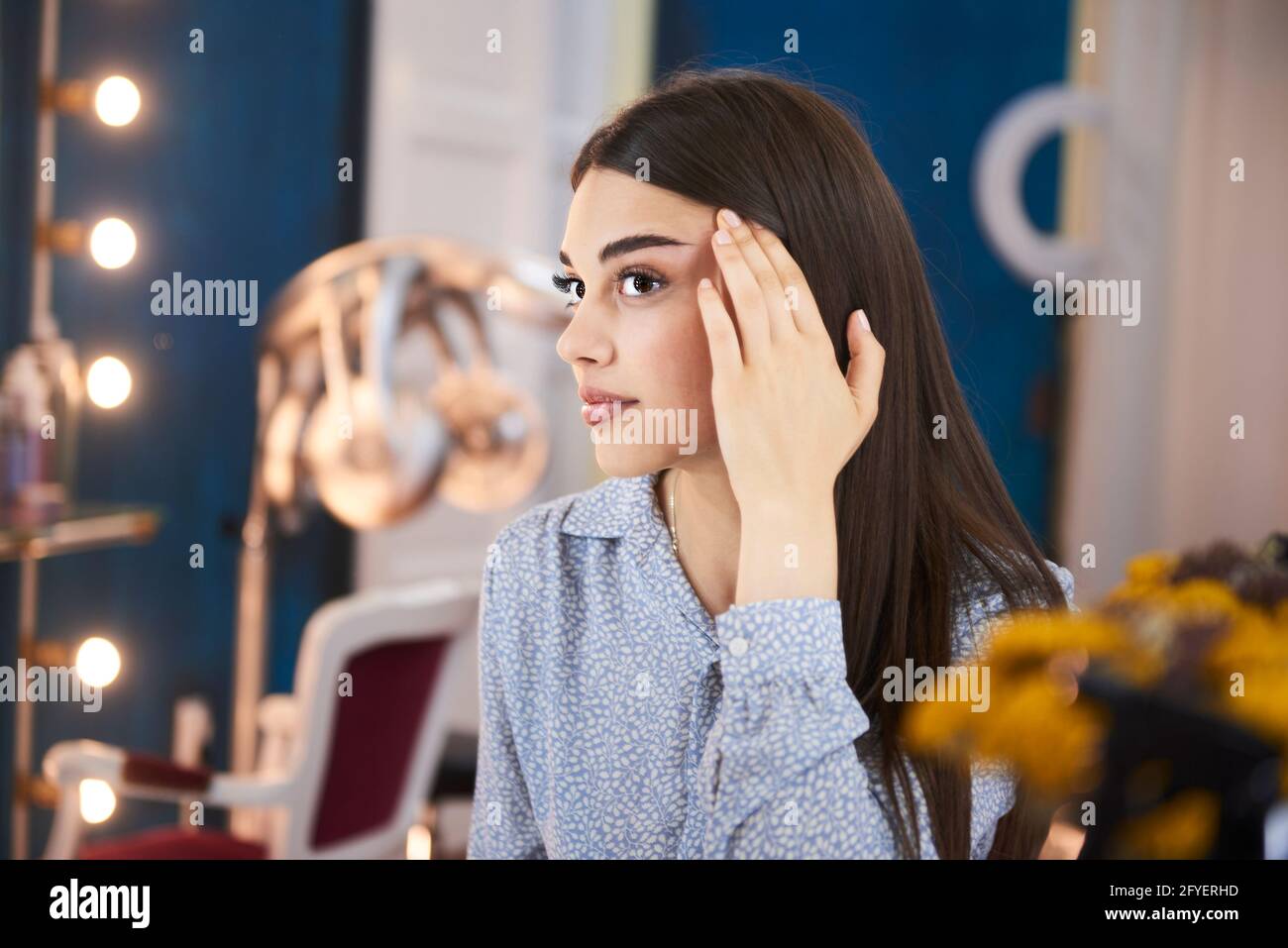 Una donna che controlla le sopracciglia al salone di bellezza Foto Stock