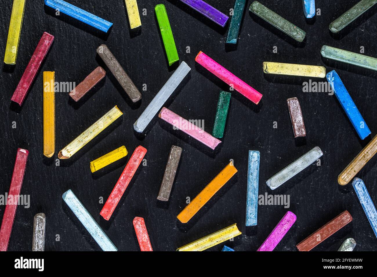 Carta da parati colorata con gessetti, motivo su sfondo nero di lavagna, concetto di ritorno a scuola, posa piatta Foto Stock