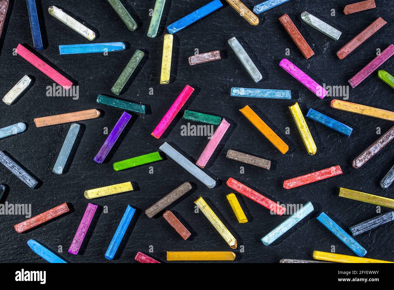 Motivo colorato per la carta da parati con gessetti colorati su sfondo nero  di lavagna, concetto di ritorno a scuola, posa piatta Foto stock - Alamy