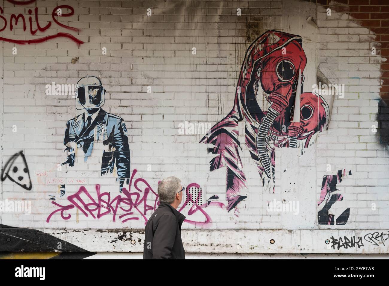 L'uomo cammina sbucciando un murale di carta in quello che sembra collegare le maschere antigas e la pandemia di coronavirus - Barnsley, South Yorkshire, Inghilterra Foto Stock