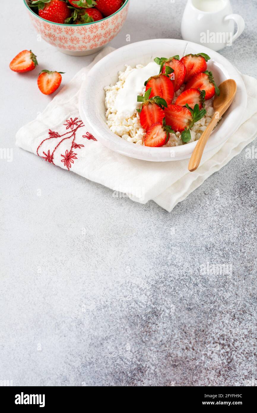 Formaggio di cottage, formaggio di cagliata con fragole in una ciotola, prodotto caseario artigianale di produzione agrana. Prodotto caseario sano ricco di calcio e proteine. Foto Stock