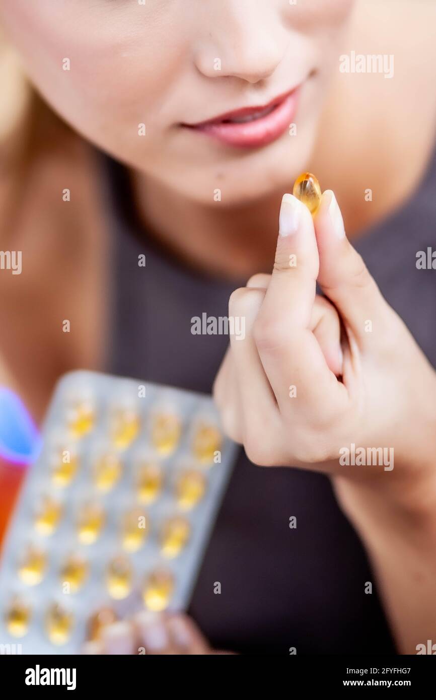 Donna prendendo integratore alimentare capsule. Foto Stock