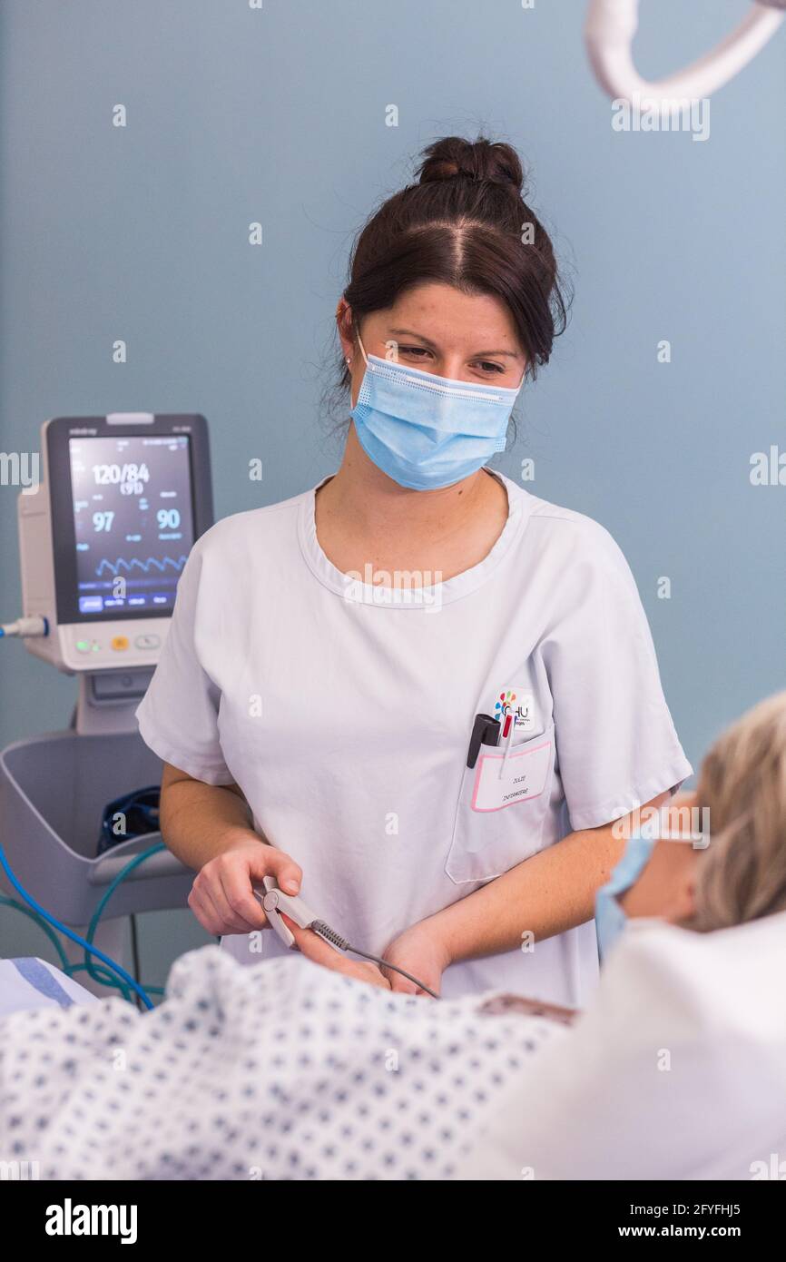 Infermiere con un paziente ricoverato. Limoges Hospital, Francia, determinazione della saturazione ossigeno-emoglobina del sangue con un pulsossimetro. Foto Stock