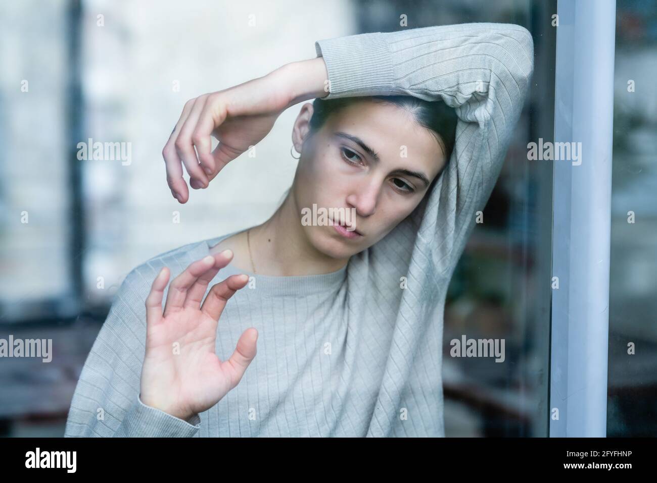 Giovane donna dietro una finestra. Foto Stock