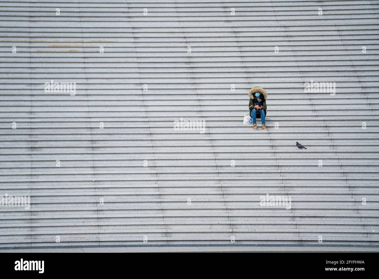 Persona seduta da sola sulle scale durante la pandemia. Foto Stock