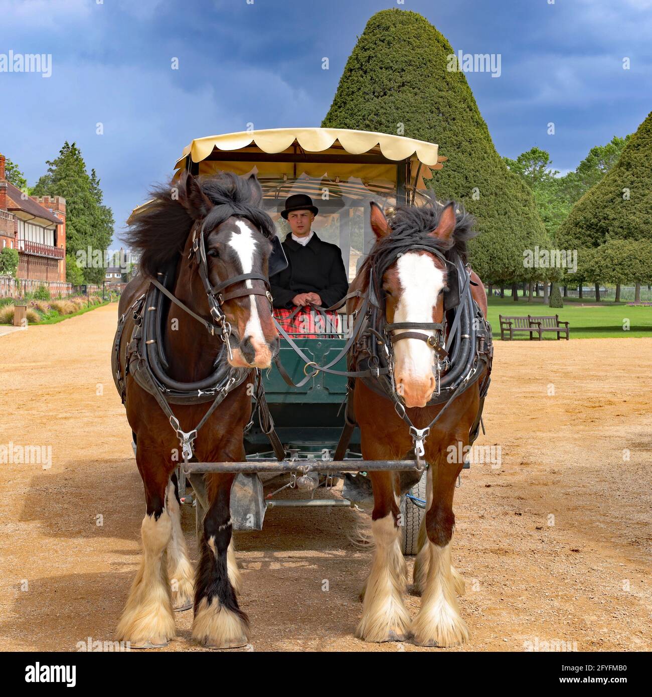 Carrozza trainata da cavalli con autista in abiti tradizionali in attesa di passeggeri nei East Front Gardens, Hampton Court Palace, Londra, Inghilterra, Regno Unito Foto Stock