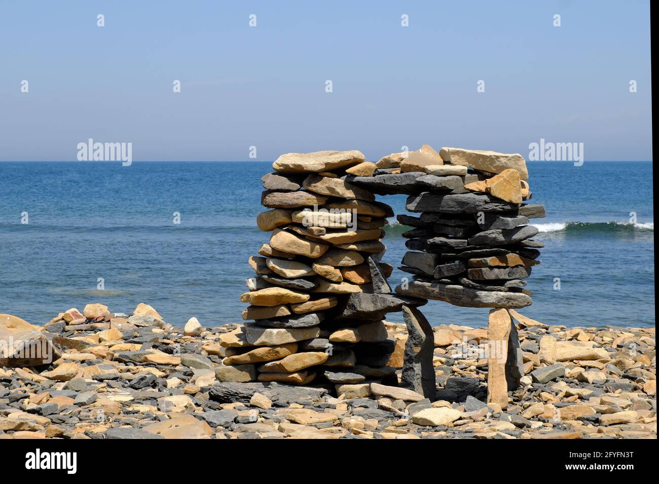 Una pila di pietre piatte, impilate da vacanzieri sulla costa rocciosa del mare in una bizzarra struttura di equilibrio complesso. Foto Stock