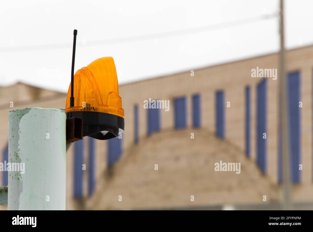 Segnalatore luminoso di allarme con antenna per la trasmissione del segnale di allarme sul tubo. Lampada di segnalazione su un palo di metallo sullo sfondo della casa. Il concetto di industria, costruzione, salute e sicurezza. Foto Stock