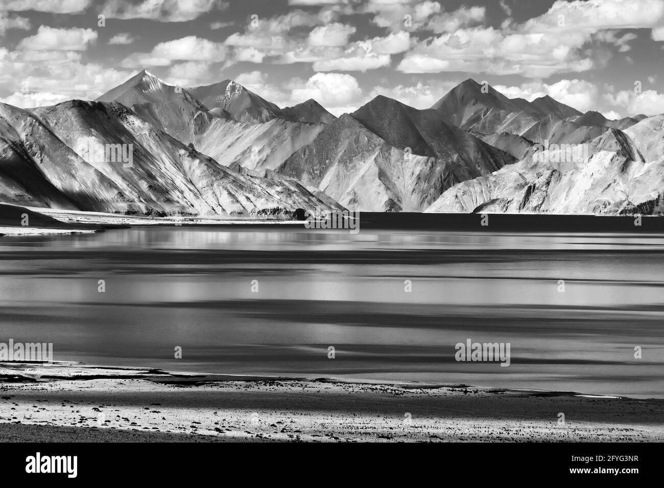 Rocce e riflesso delle montagne su Pangong Tso (Lago). E' un enorme lago a Ladakh, in India. India frontiera con la Cina. Foto Stock