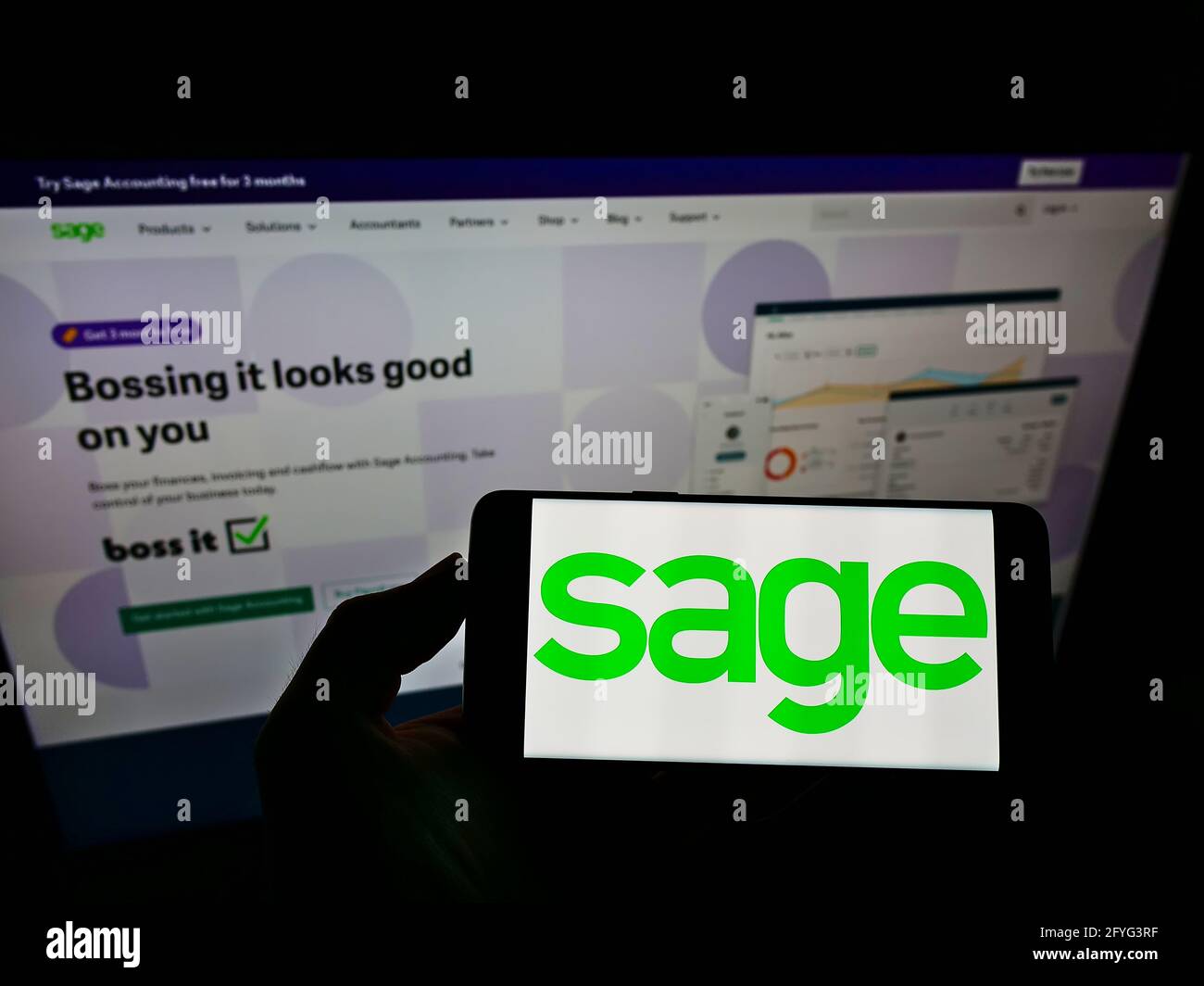 Persona che detiene smartphone con il logo della società di software britannica The Sage Group plc sullo schermo di fronte al sito web. Mettere a fuoco il display del telefono. Foto Stock