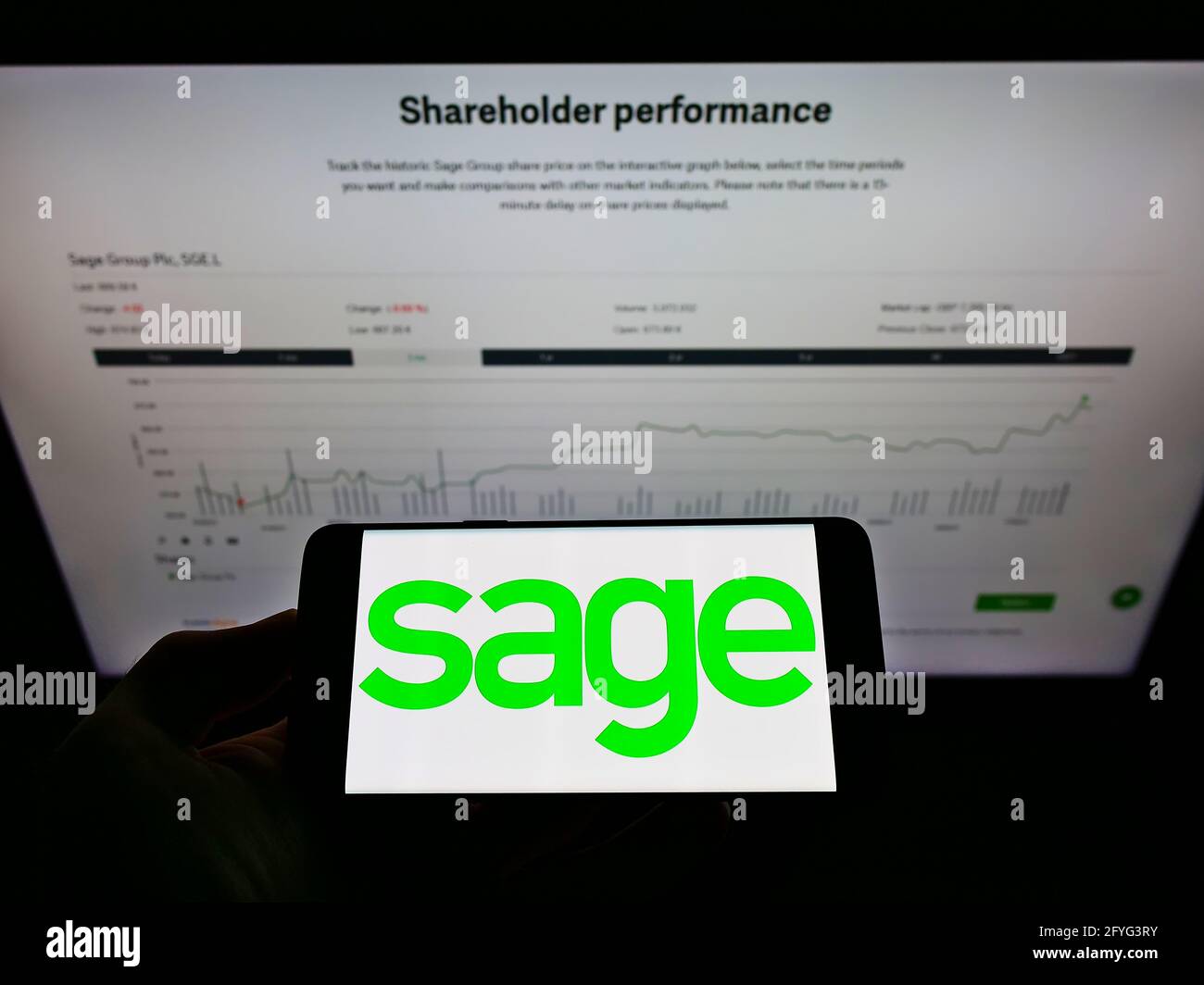 Persona che detiene il telefono cellulare con il logo aziendale della società di software britannica il gruppo Sage plc sullo schermo di fronte alla pagina web. Mettere a fuoco il display del telefono. Foto Stock