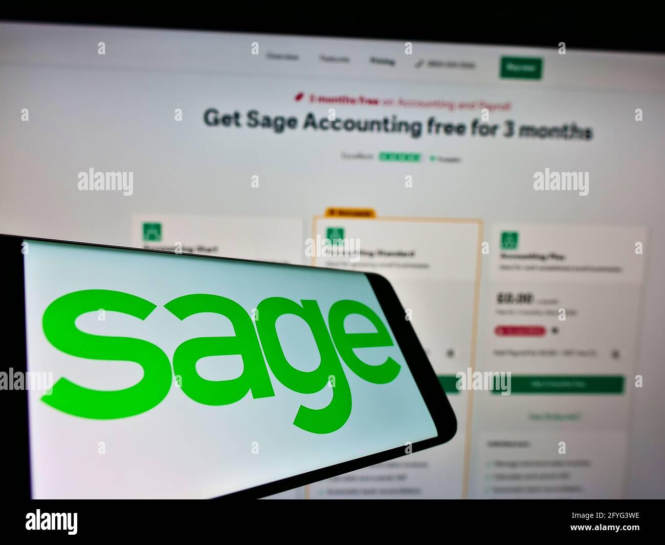 Smartphone con logo della società di software ERP britannica il gruppo Sage plc sullo schermo di fronte al sito web aziendale. Mettere a fuoco il centro del display del telefono. Foto Stock