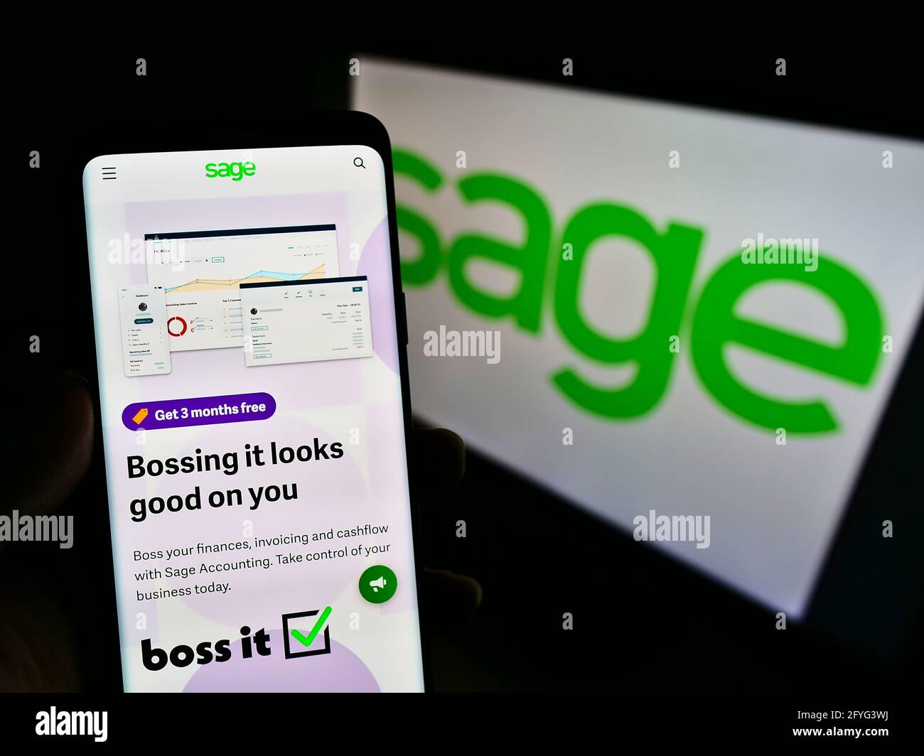 Persona che tiene il telefono cellulare con la pagina web della società di software britannica il gruppo Sage plc sullo schermo davanti al logo. Mettere a fuoco il centro del display del telefono. Foto Stock