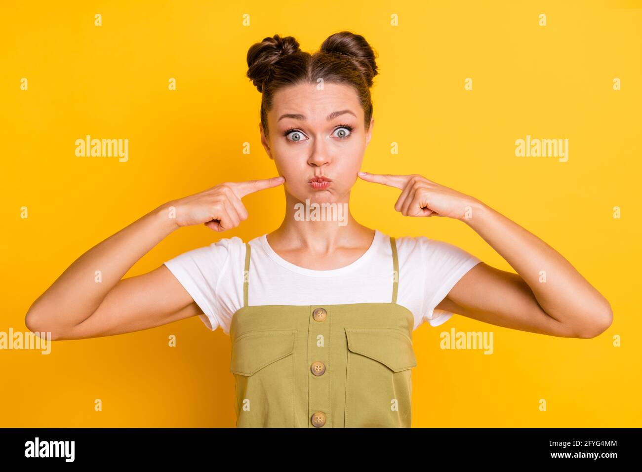 Foto di funky signora gonfiare guance premere le dita guardare fotocamera usura di fondo giallo isolato verde Foto Stock