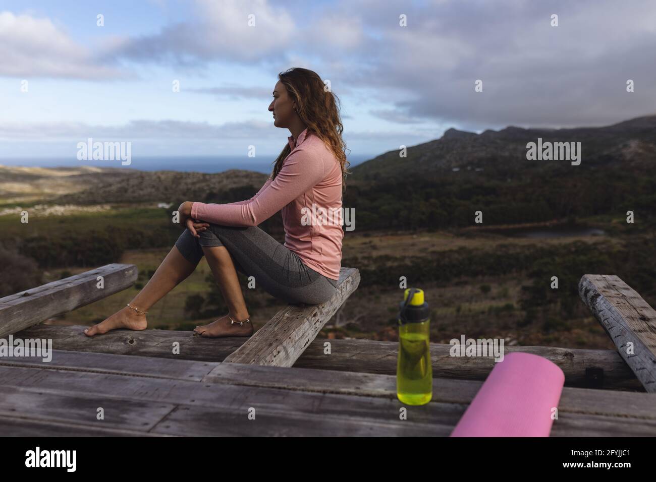 Donna caucasica premurosa seduta sul ponte ammirando la vista in ambiente rurale di montagna Foto Stock