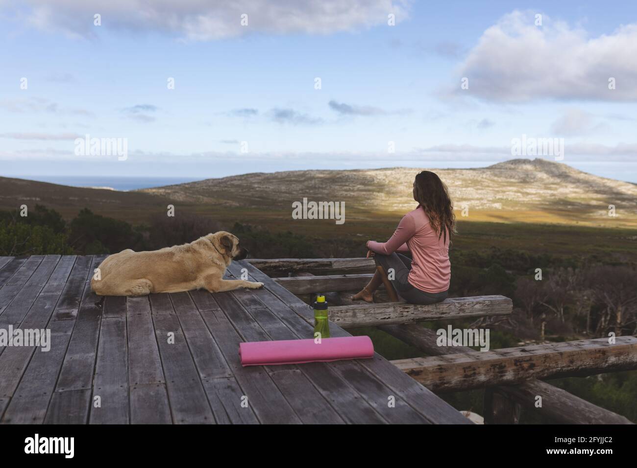 Donna caucasica premurosa seduta sul ponte con cane animale domestico che si ammira la vista in montagna rurale Foto Stock