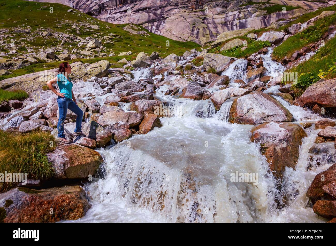 Donna in piedi su rocce da una cascata, Gelmersee, Svizzera Foto Stock