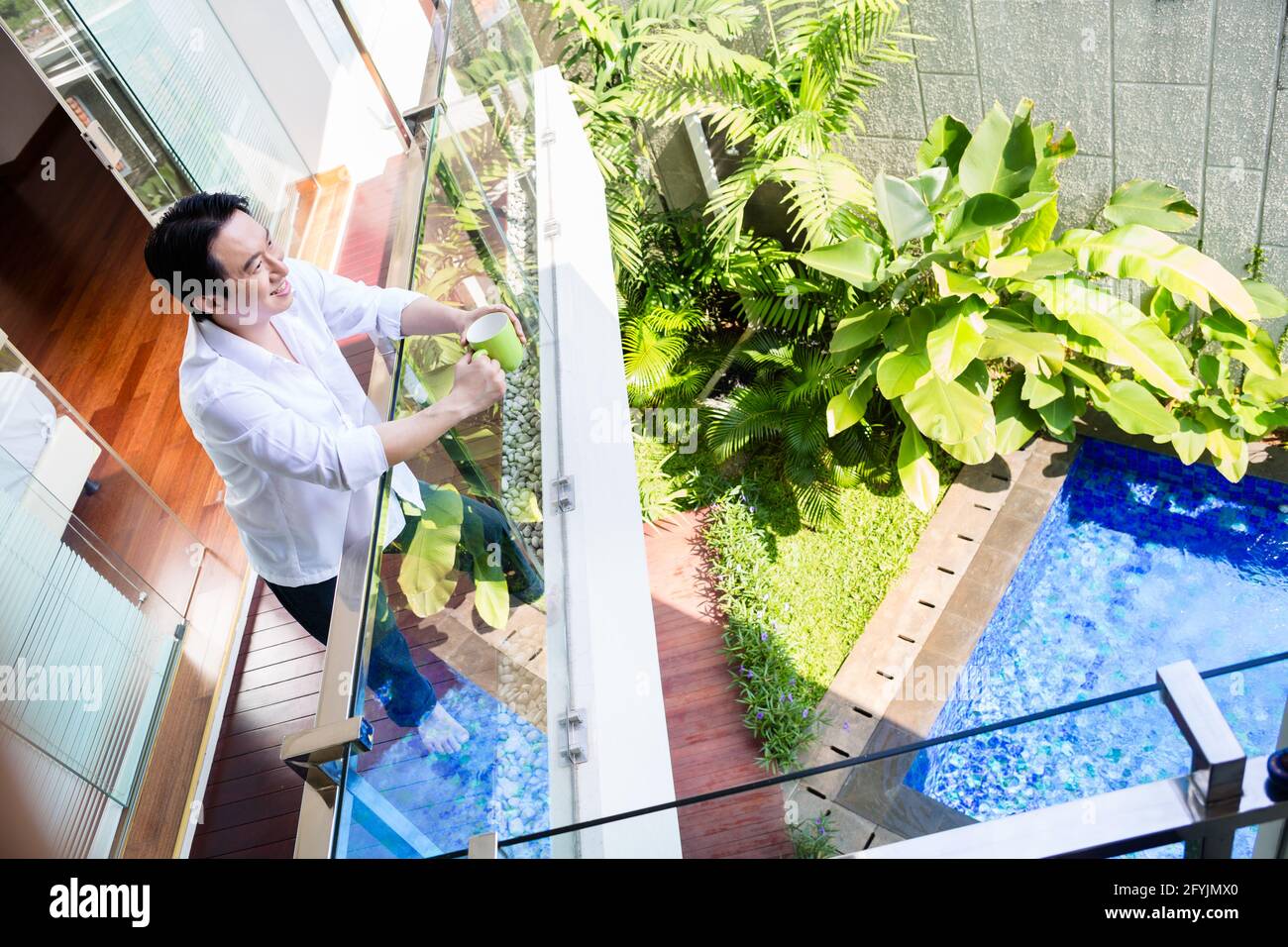 Uomo cinese sul balcone di casa con caffè guardando piscina con giardino  Foto stock - Alamy